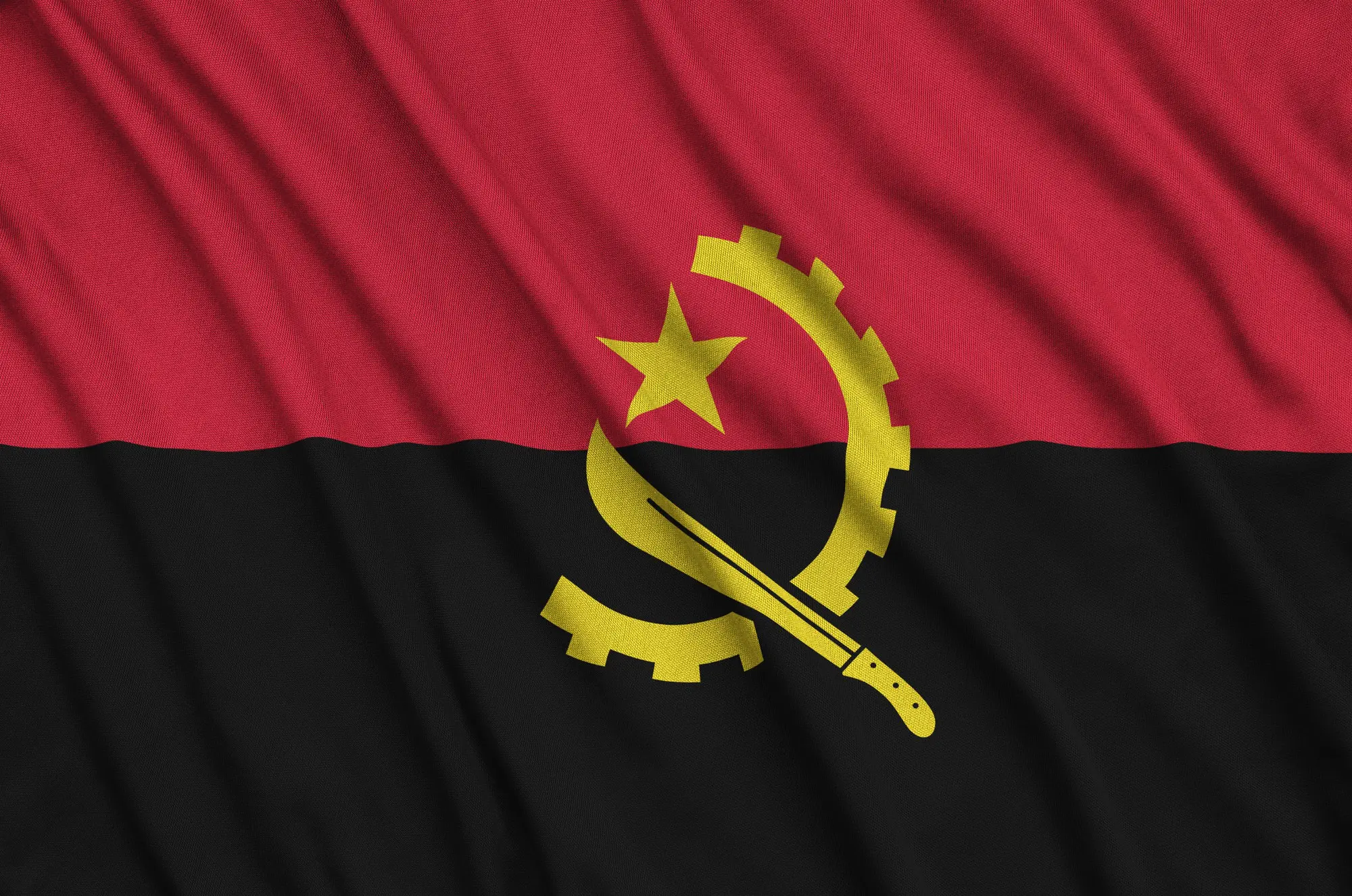 Angola flag is depicted on a sports cloth fabric with many folds. Sport team waving banner