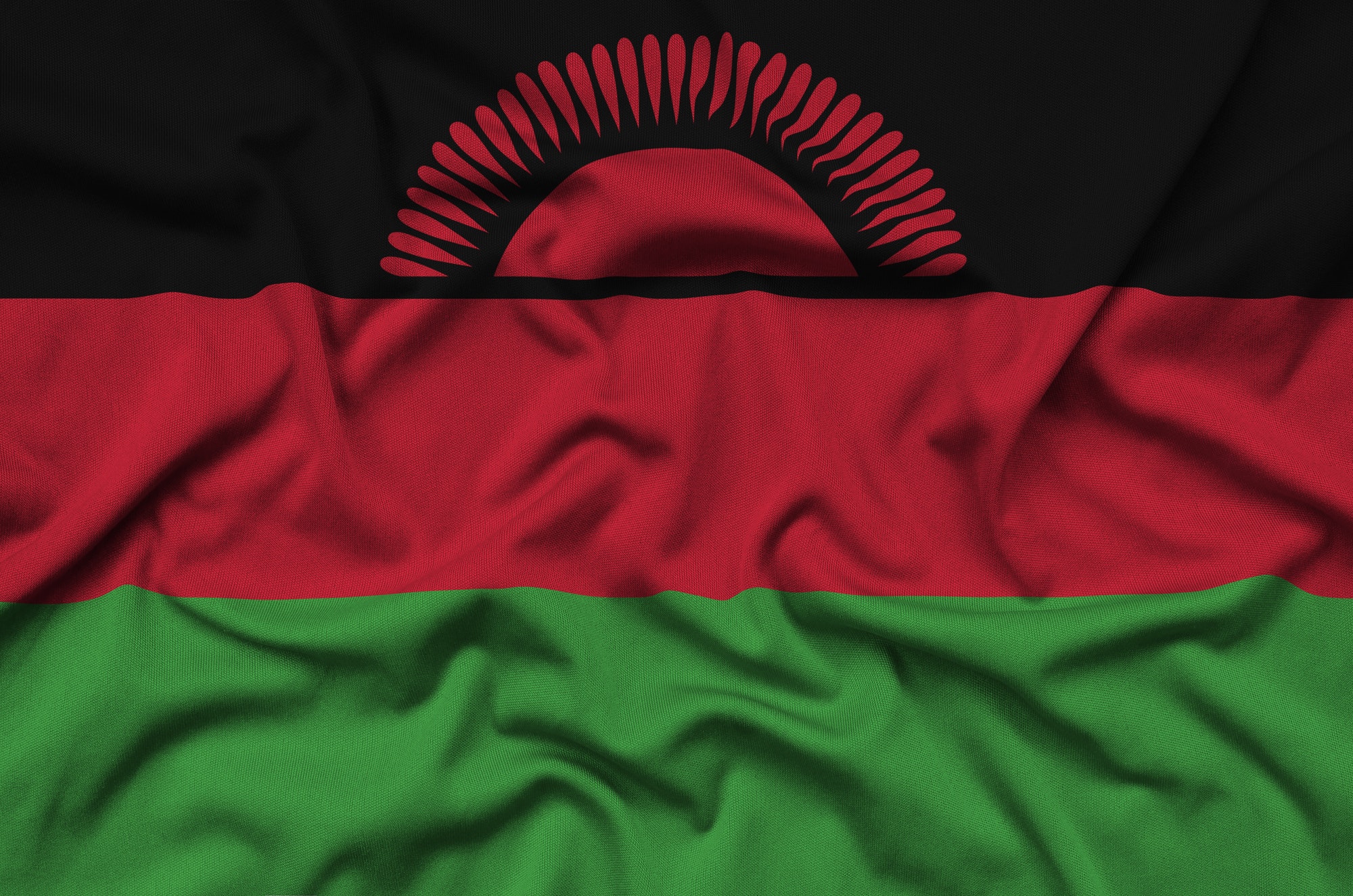 Malawi flag is depicted on a sports cloth fabric with many folds. Sport team waving banner